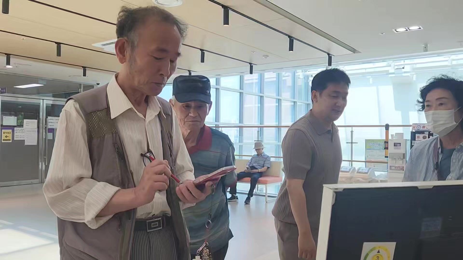 복지관에서 어르신들이 스마트폰으로 체형 분석 앱을 확인하는 모습